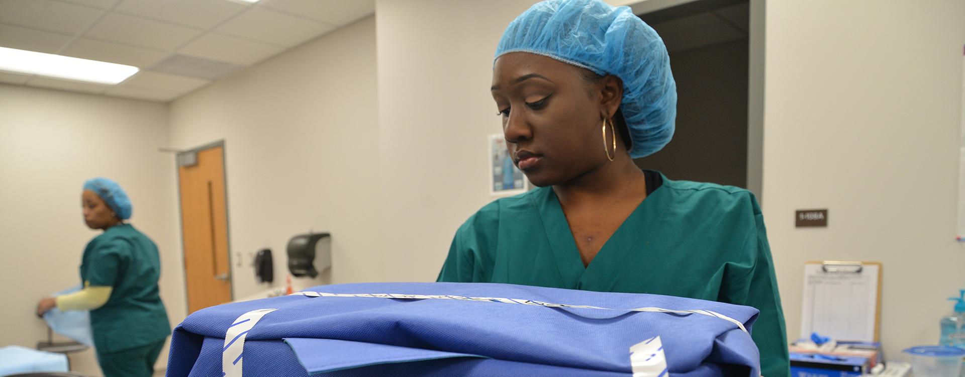 student carries a surgical tray wrapped in sterilized cloth