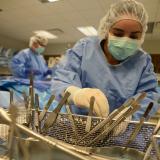 student with surgical mask and gloves looking over surgical tools