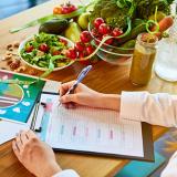 dietitian surrounded by fruits and vegetables writing a meal plan 
