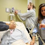 respiratory therapy students practice how to administer oxygen and take a patient pulse in lab